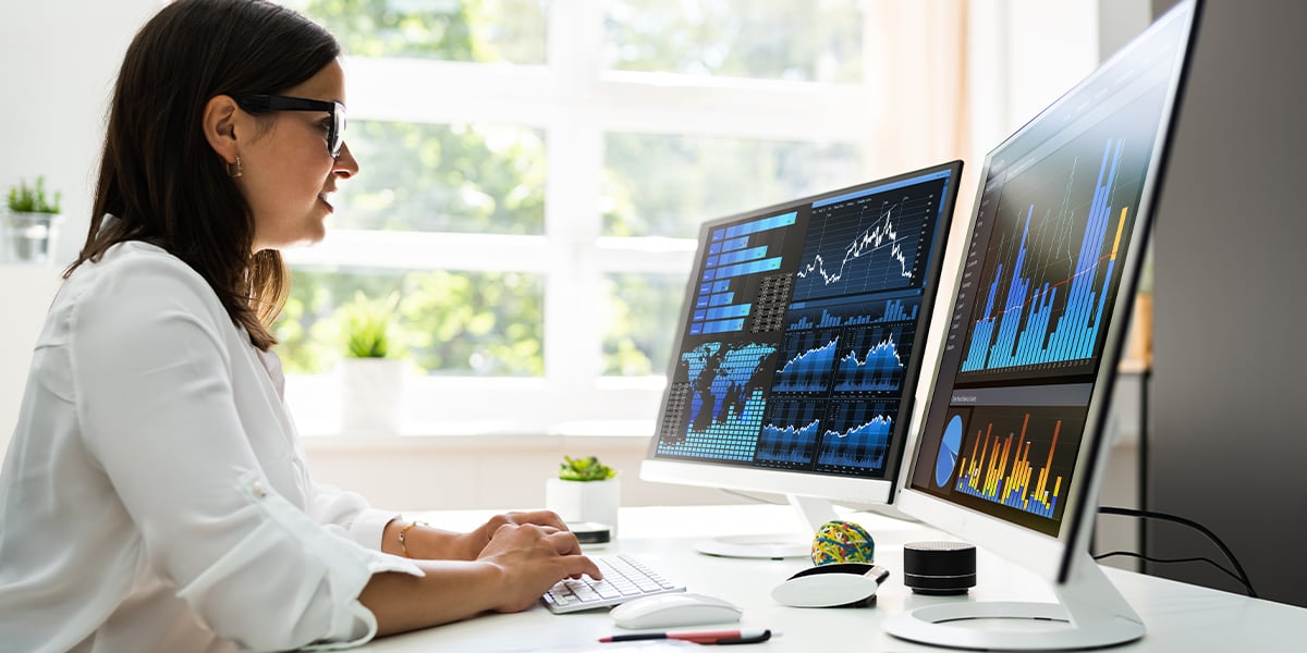 A woman looking at data on a desktop computer in her office.
