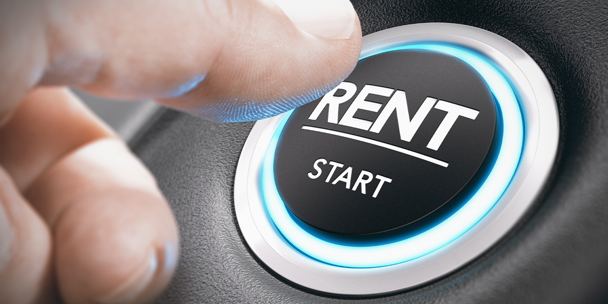 Closeup of a person pressing a large start button on car with the word "RENT" above "START"