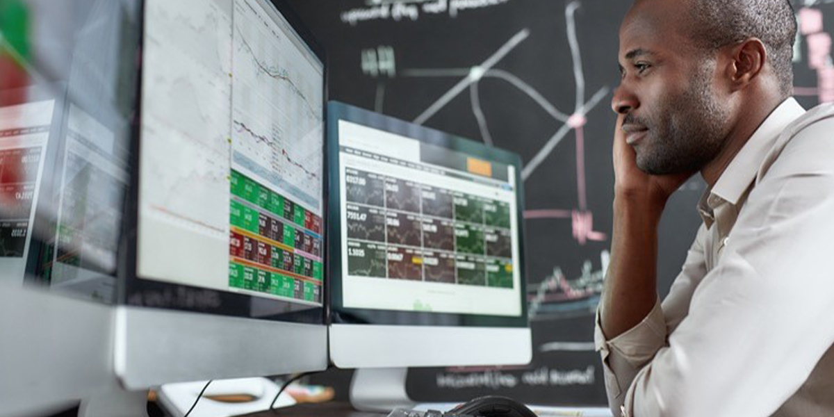 A man looking at data on a desktop computer in his office.